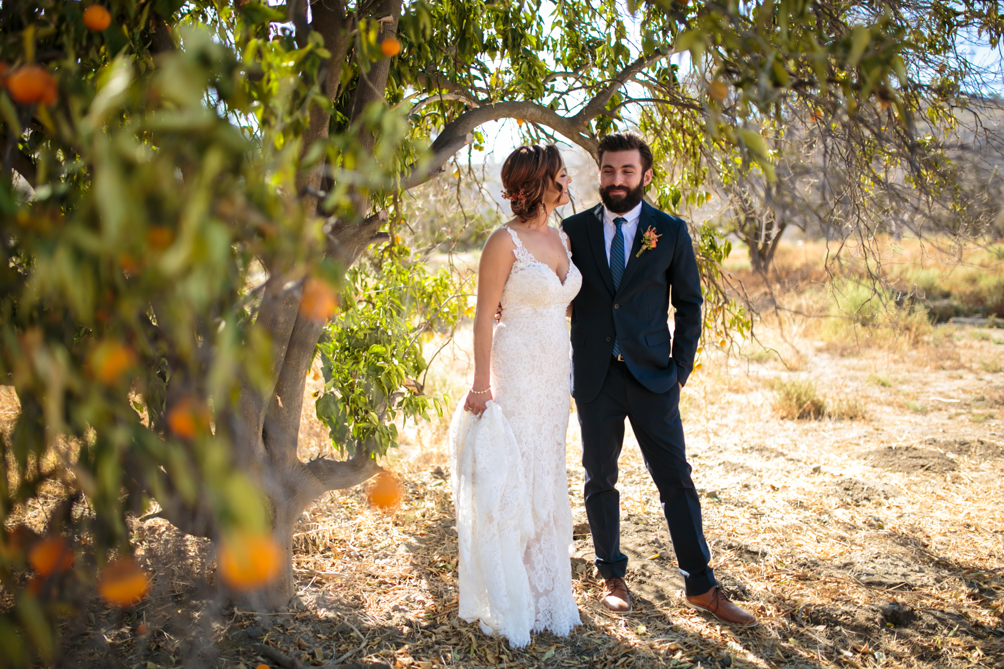 Couple stands under an orange tree.