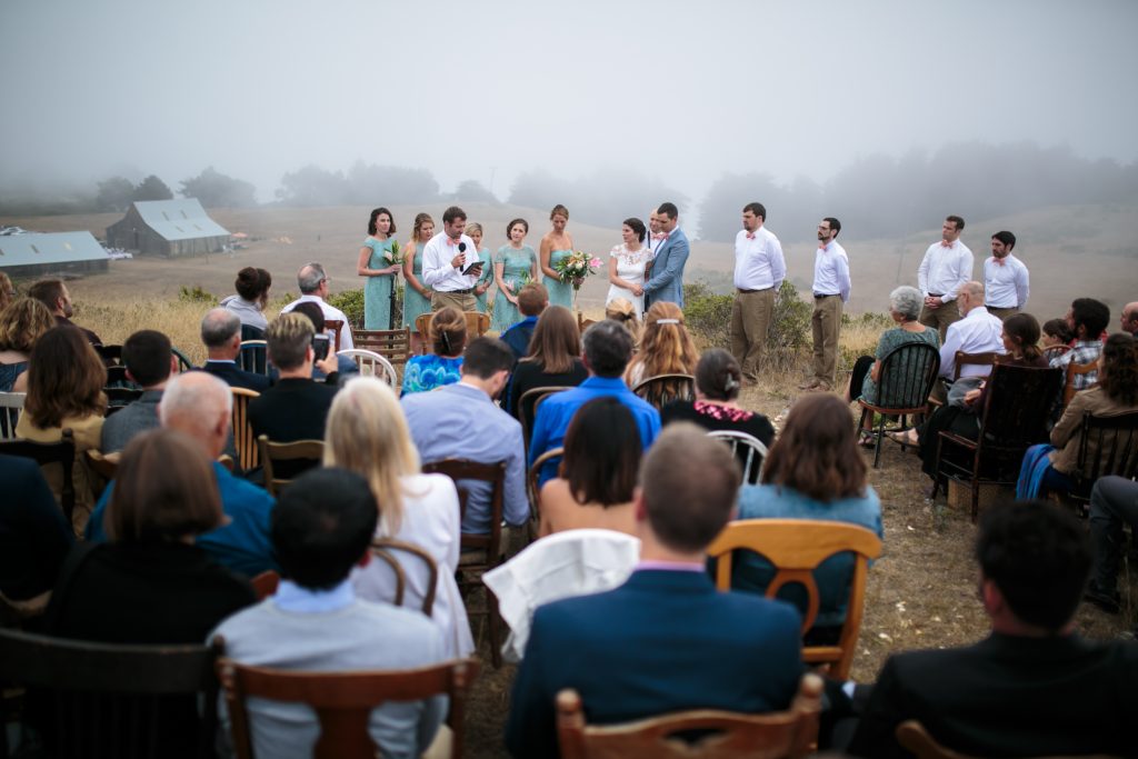 A foggy Mendocino hillside wedding with a barn in the distance.