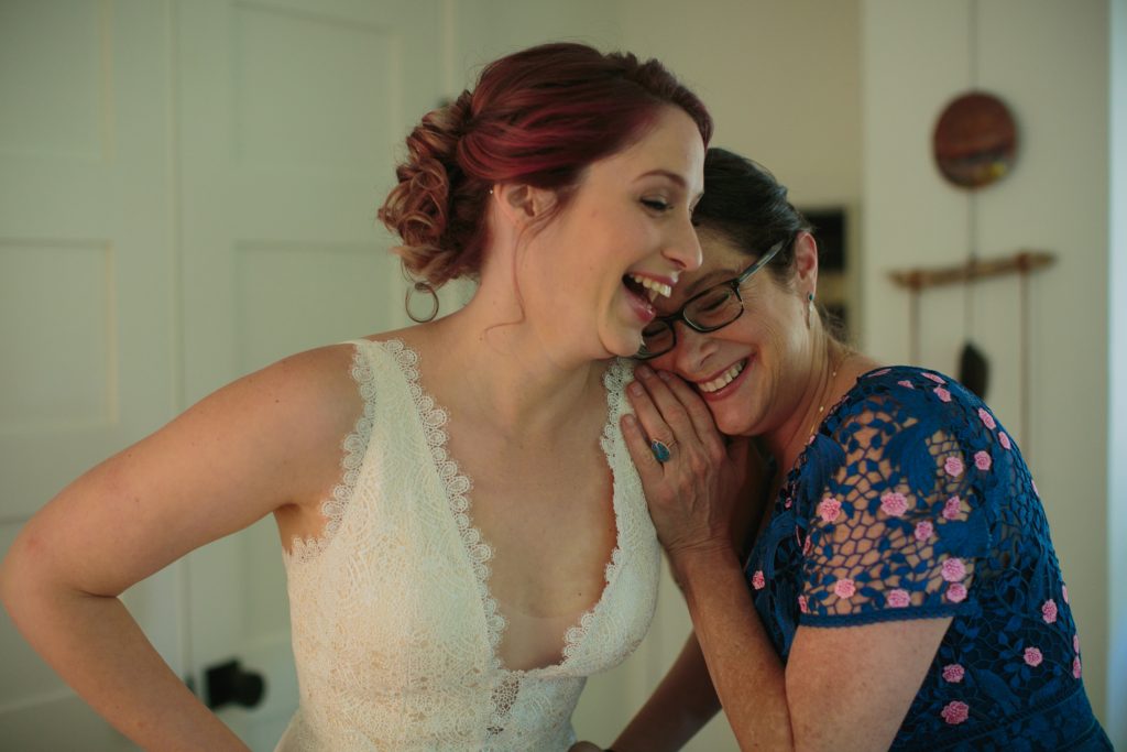 Bride laughing with her mother while getting ready for the wedding.