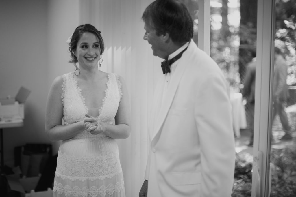 Bride and father-daughter smiling at each other as he enters the room and sees her for the first time.