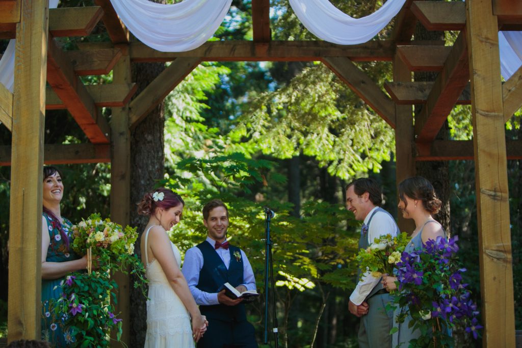 Bride and groom during their wedding ceremony under a white canopy and beautiful wood trellis.