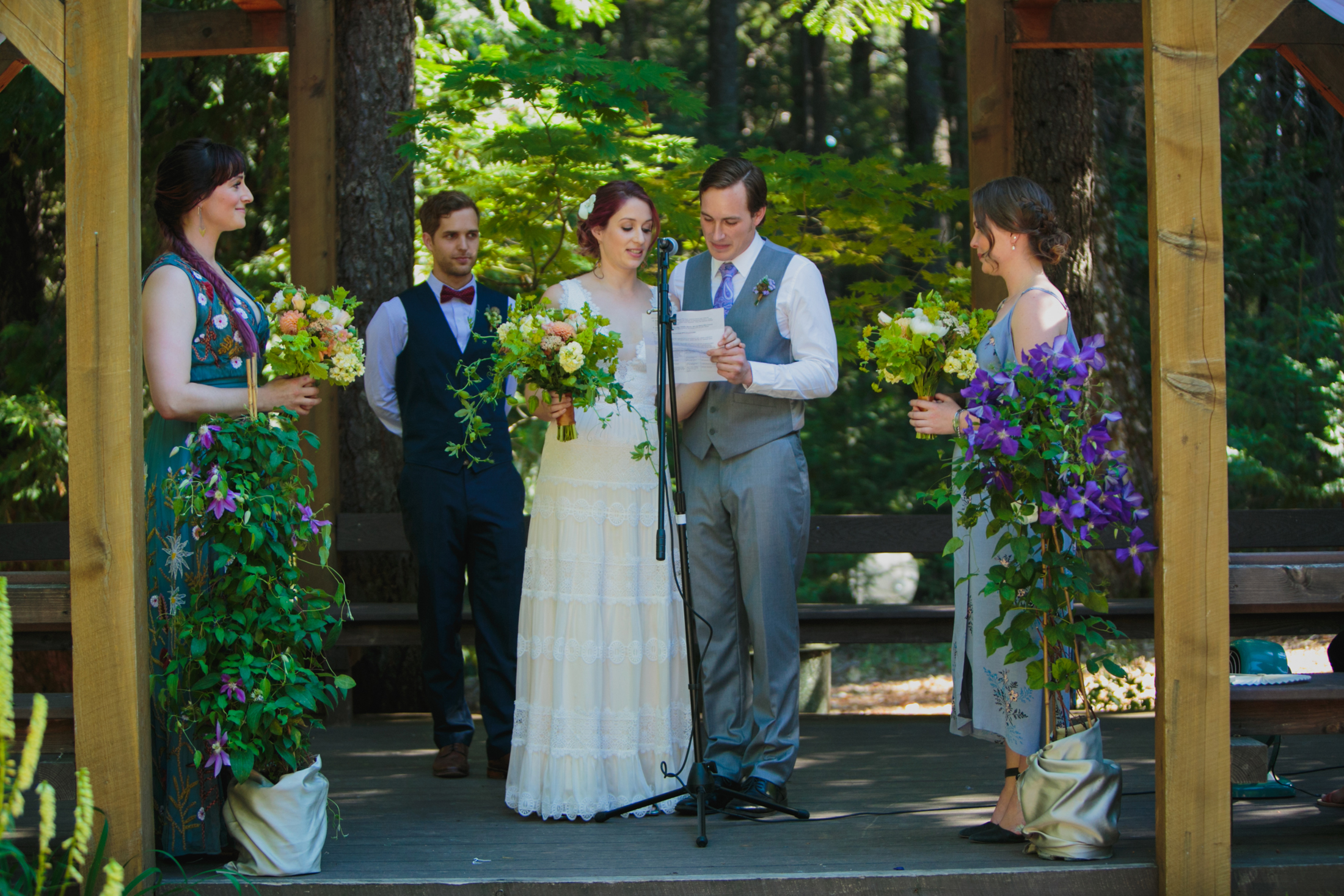 The bride and groom read their vows together off of a shared piece of paper.