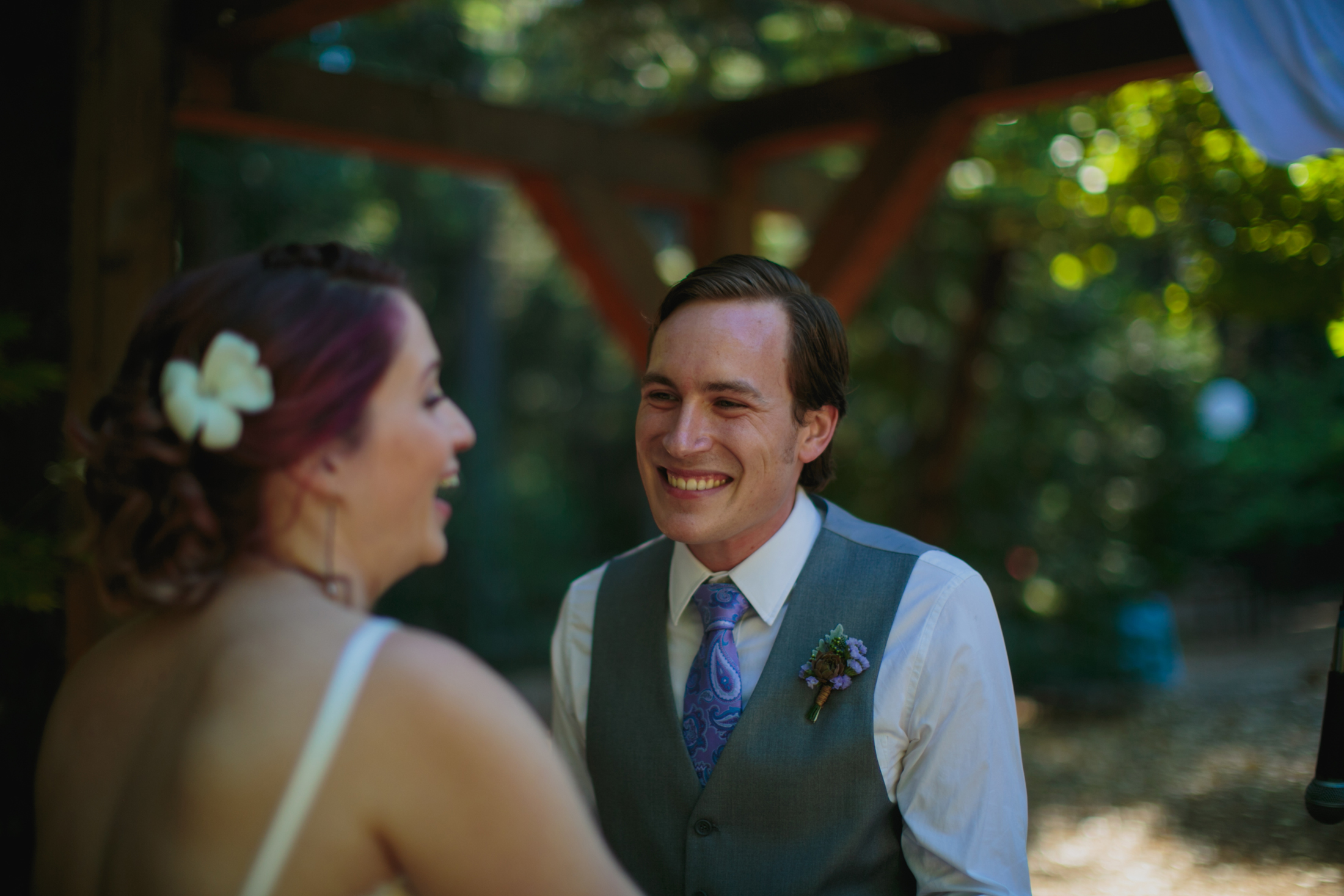 The groom is smiling at his bride while she laughs looking at their guests.
