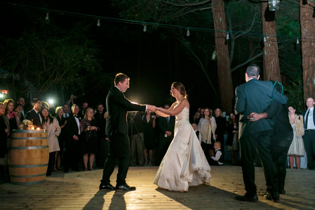 The bride and groom facing each other holding hands while dancing.