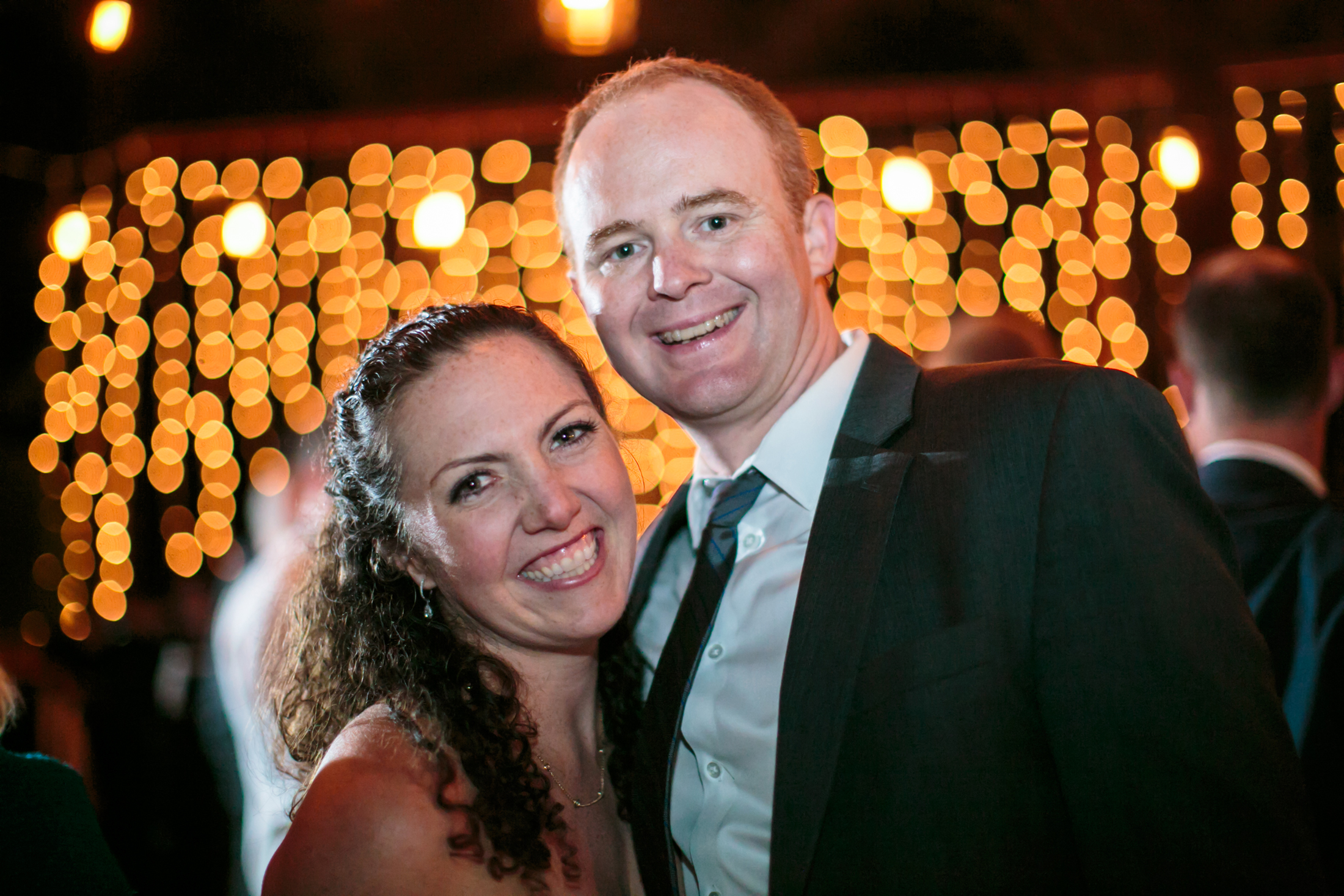 Smiling guests in front of a very sparkly, bokeh background.