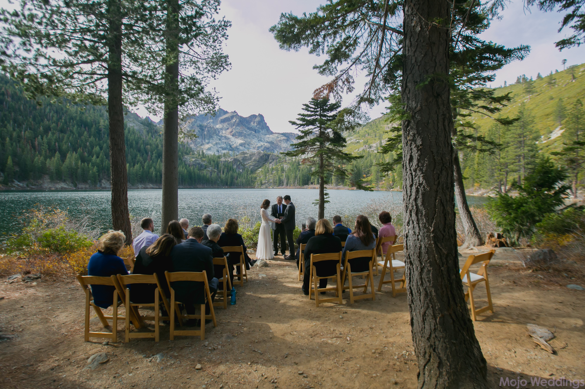 Guests are seated as the wedding ceremony takes place in front of the lake.