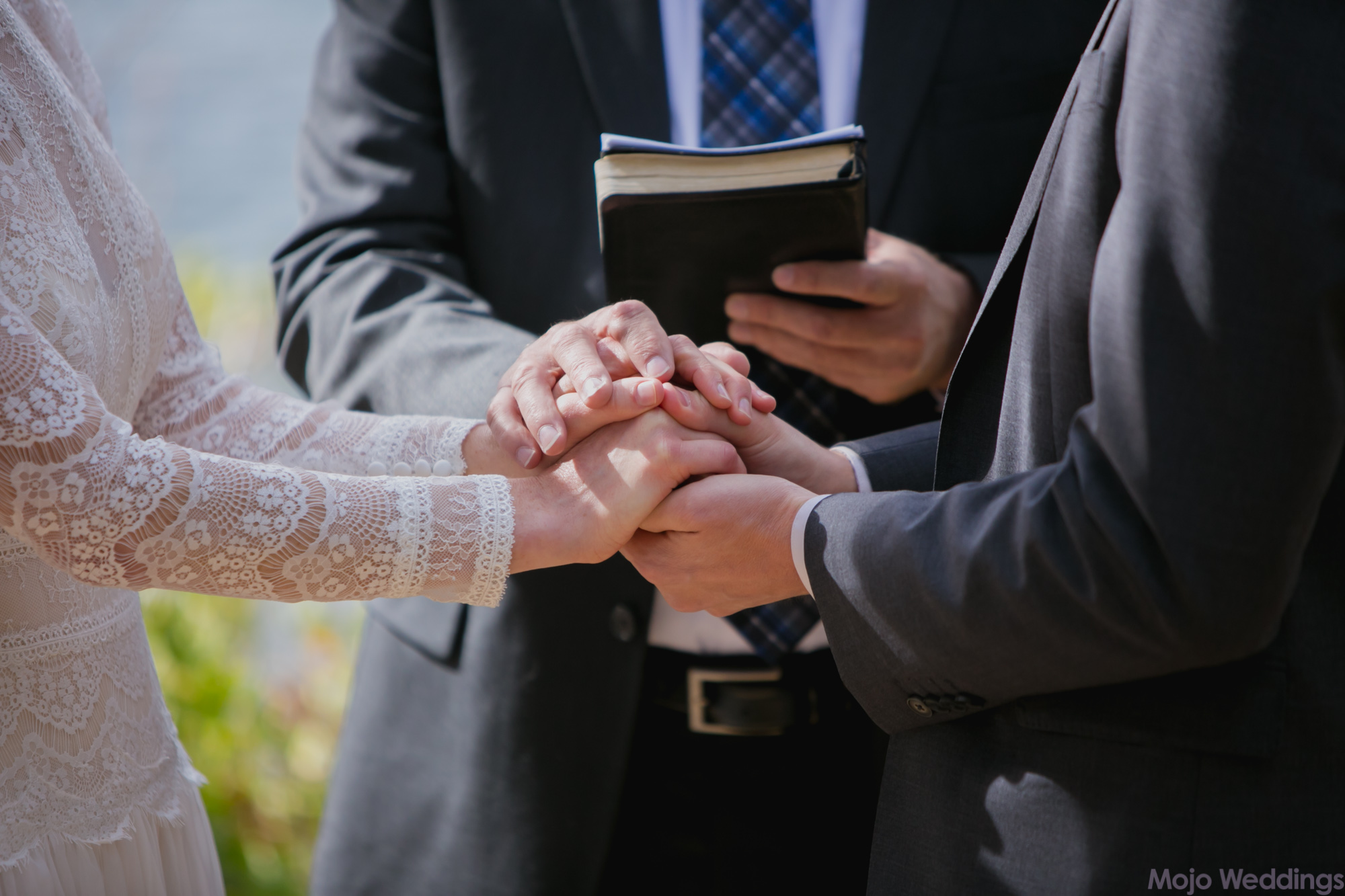 A close up of the hands of the bride, groom, and officiant.