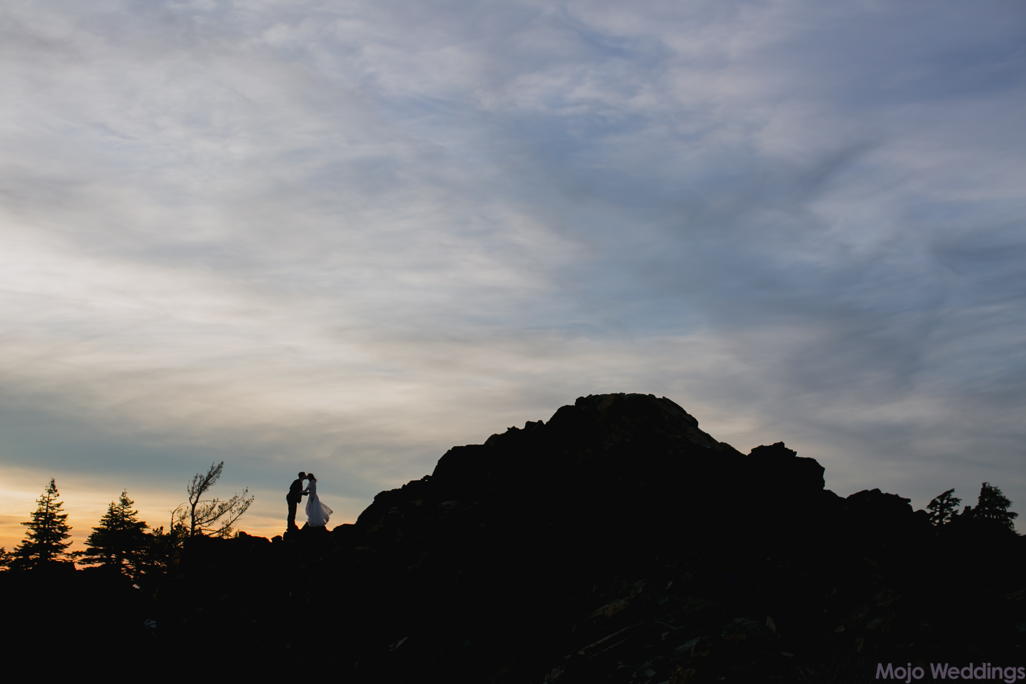 A silhouette of the bride and groom along the peak of the mountain.